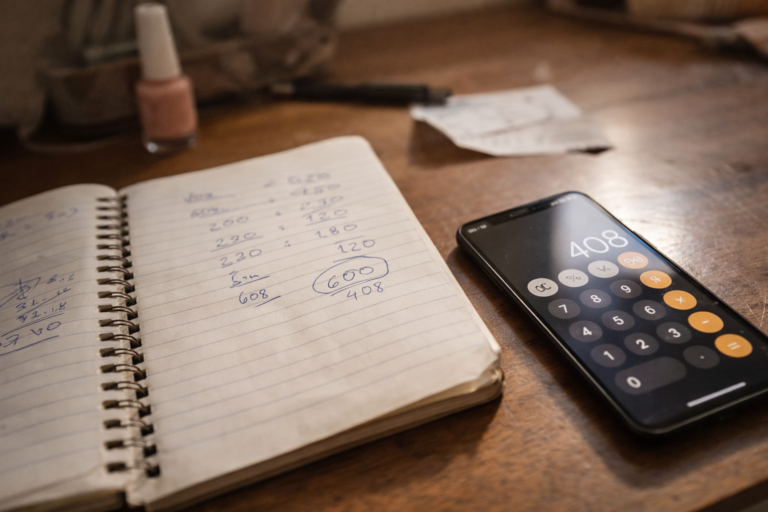 Como calcular o preço do serviço em mesa de trabalho de prestadora de serviço com caderno de cálculos e celular com calculadora
